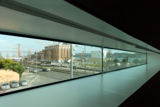 Abertura na parede externa do saguão expositivo. Ao fundo o Museu da Eletricidade e o Tejo