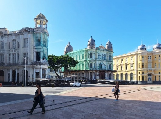 Vista do conjunto de edifícios de destaque do Marco Zero com seus característicos torreões e cúpulas; à esquerda, protegido por tela, um dos edifícios em risco, 2023