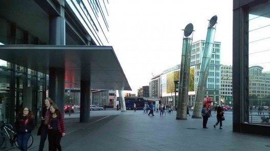 Panorâmica entre o prédio de Renzo Piano e o Pórtico de entrada da estação de metrô. Detalhe para as torres de captação de luz natural