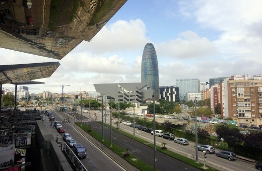 À esquerda, Mercado dos Encantos, confluência da Avenida Meridiana e a praça das Glorias, com torre Agbar ao fundo. Originalmente planejada por Ildefonso Cerdà em 1859, a Meridiana liga o Parc de la Ciutadella, cruzando a Plaça de les Glòries (Poblenou)