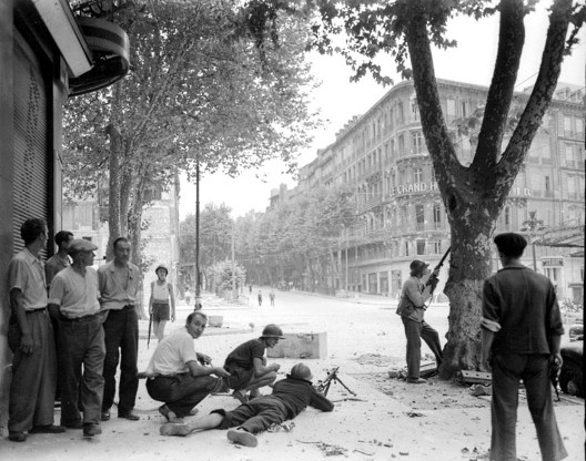 Membros da resistência francesa lutam contra soldados alemães e colaboracionistas franceses do outro lado da rua da famosa Le Grand Hôtel, Paris, agosto 1944